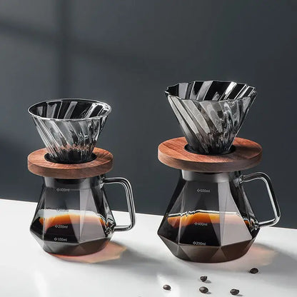 Two elegant faceted dark tinted diamond glass coffee filter cup drippers with wooden lids atop matching glass coffee carafes