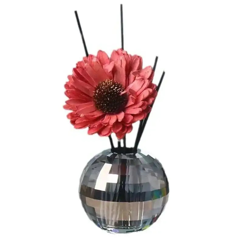 A sparkling silver disco ball aroma diffuser with a geometric base, coral artificial flower, and black reeds for bedroom decor