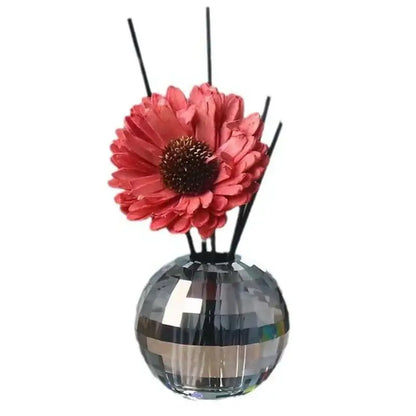 A sparkling silver disco ball aroma diffuser with a geometric base, coral artificial flower, and black reeds for bedroom decor