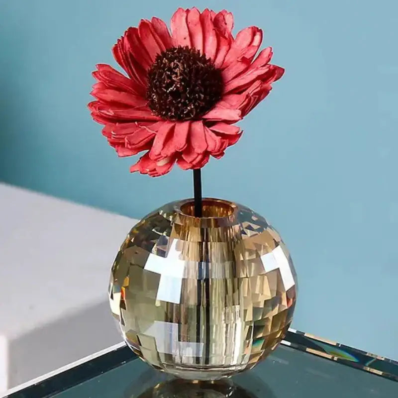 Faceted gold crystal sphere aroma diffuser with geometric base holding a single red dried flower for bedroom decor