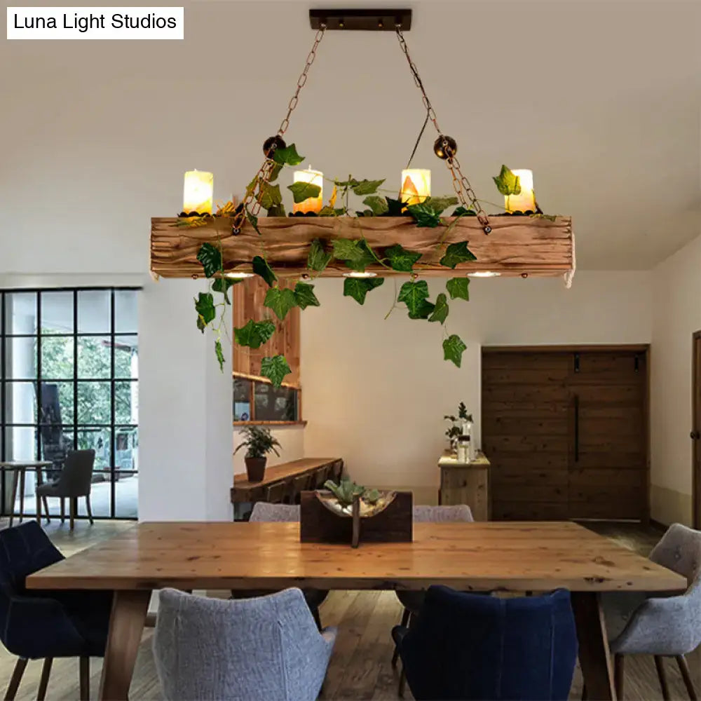 Rustic wooden linear island chandelier with hanging green ivy and candle-style lights for farmhouse dining rooms