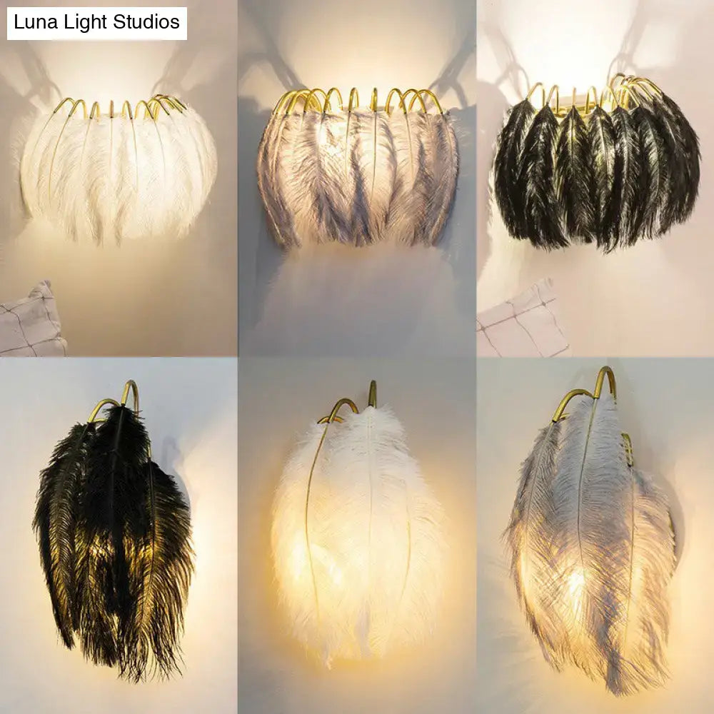 Elegant feather gold wall light fixture with gold-toned metal frame and soft white, gray, and black feathers for bedroom