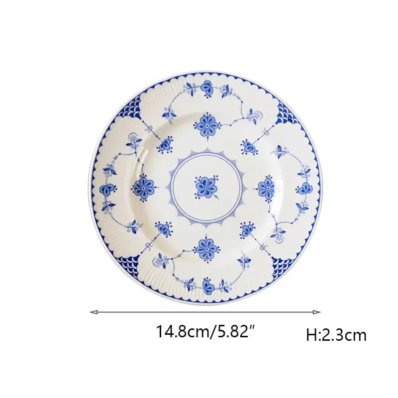 A delicate white ceramic dinner plate with intricate blue floral patterns and scalloped edge decorbites ceramic dinnerware