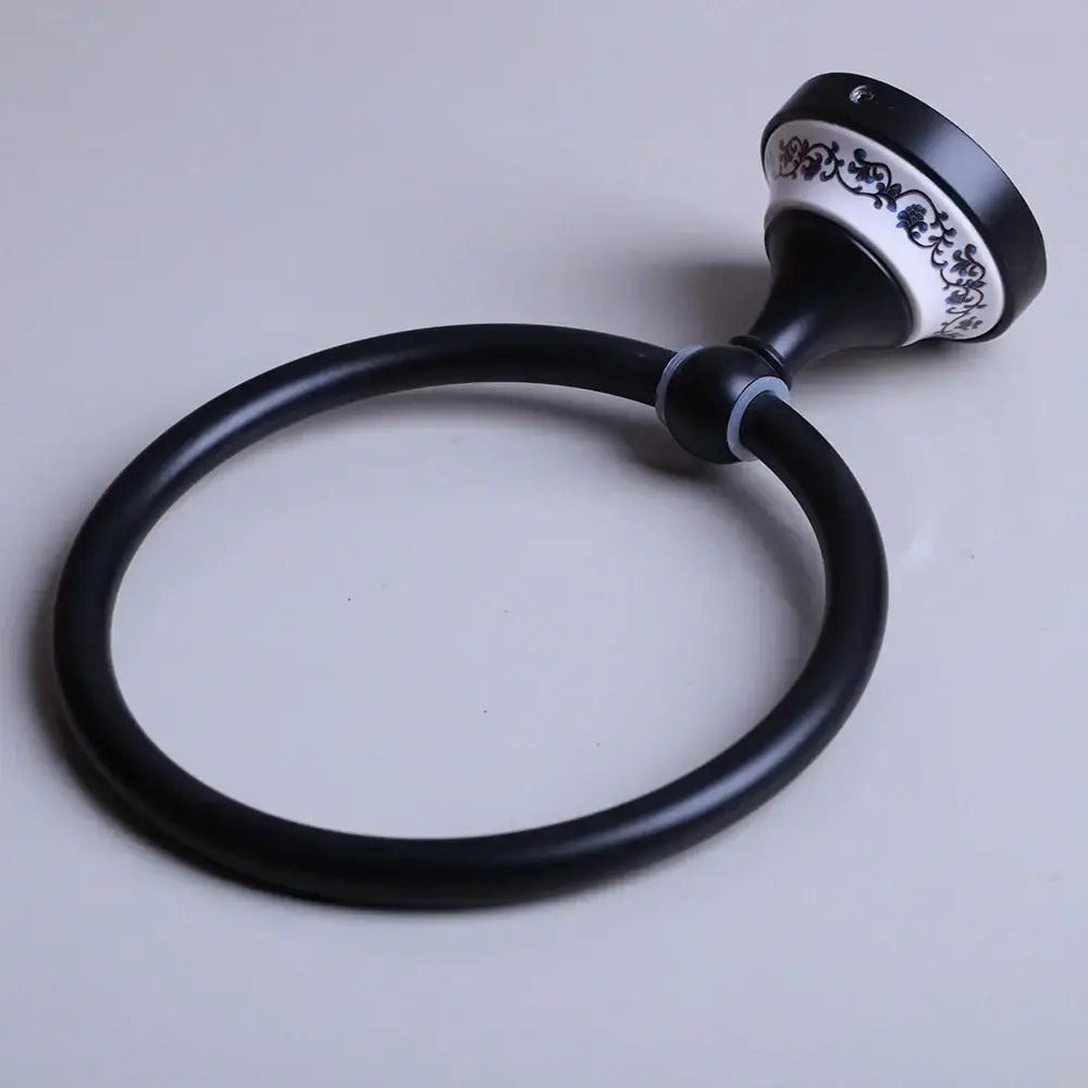 Black stainless steel towel ring with black matte finish and ornate white ceramic base featuring blue floral decorbites design