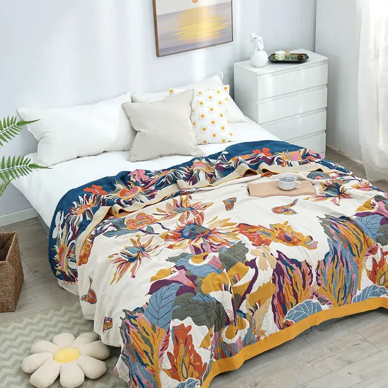 A decorbites cotton summer blanket with vibrant floral patterns in orange blue yellow and purple on a cream base