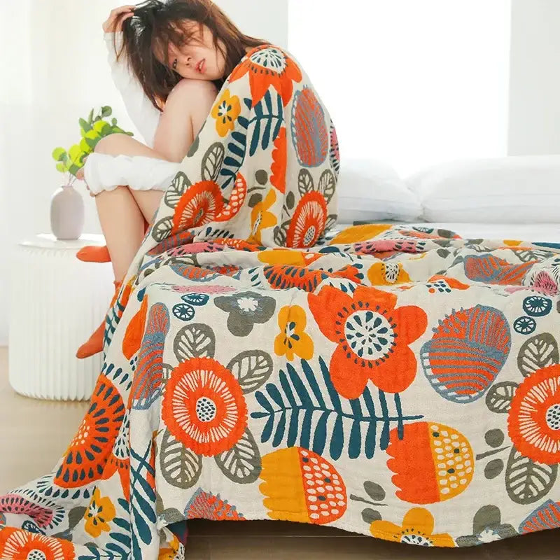 Cozy cream-colored double gauze cotton summer blanket with vibrant oversized orange, yellow, and teal floral pattern