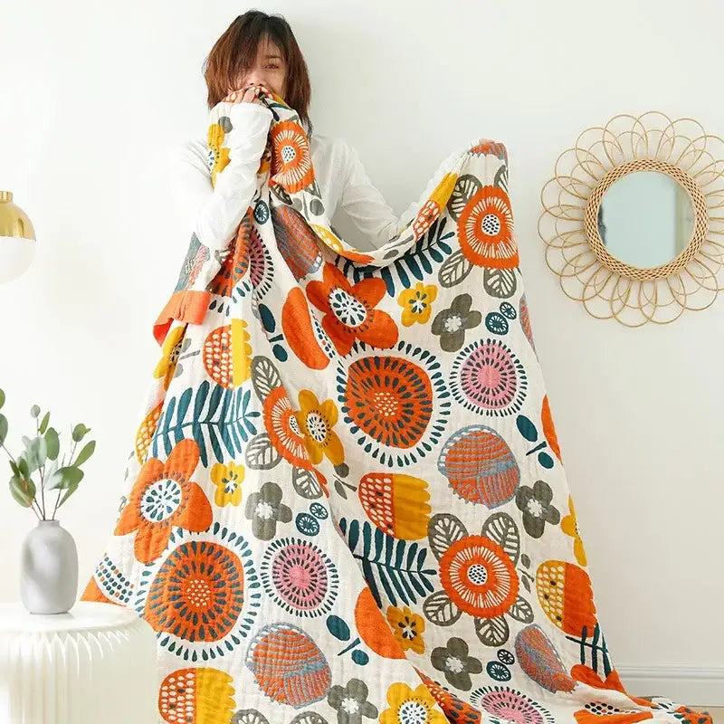 A vibrant floral cream double gauze cotton summer blanket in orange yellow pink and teal for bedroom decor
