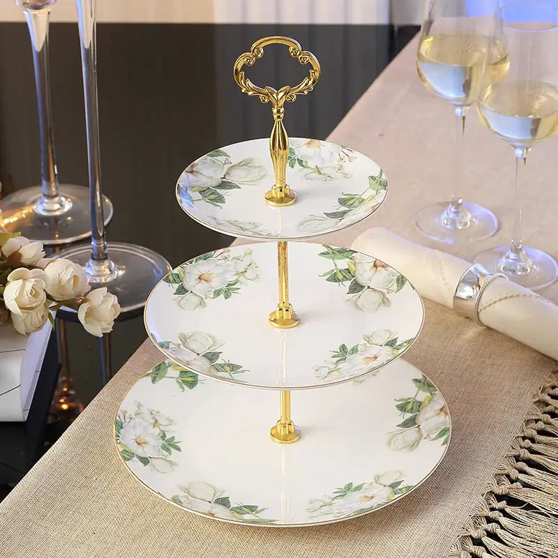Three-tiered bone china fruit plates set with gold-toned ornate handle and white floral pattern tiered stand