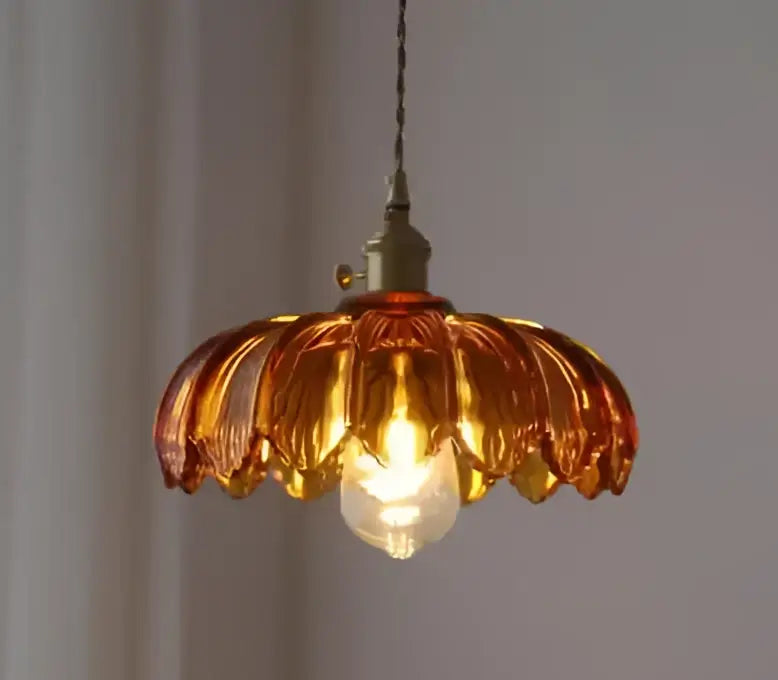Amber-colored glass pendant light with brass finish metal fixture and exposed bulb for dining room use