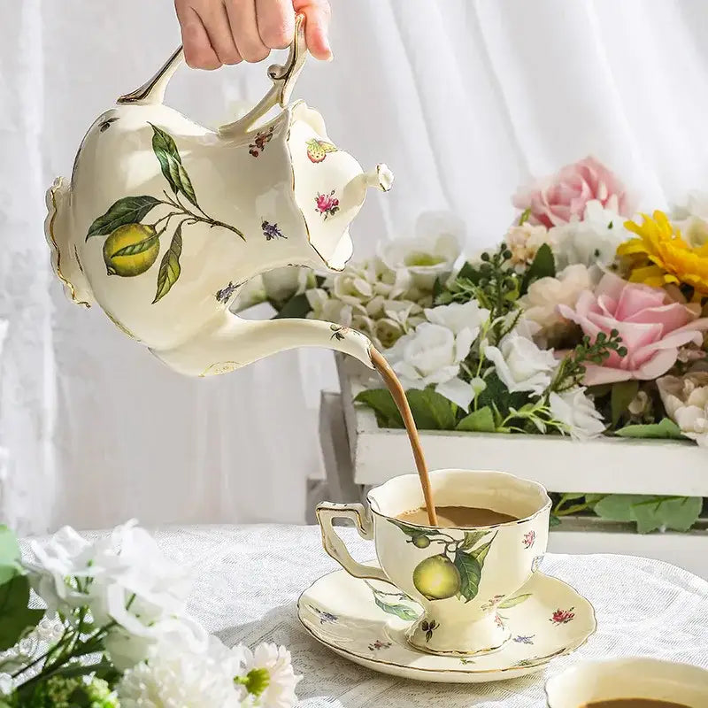 Cream-colored porcelain tea set teapot with delicate lemon floral illustrations and gold trimmed edges for dining room use
