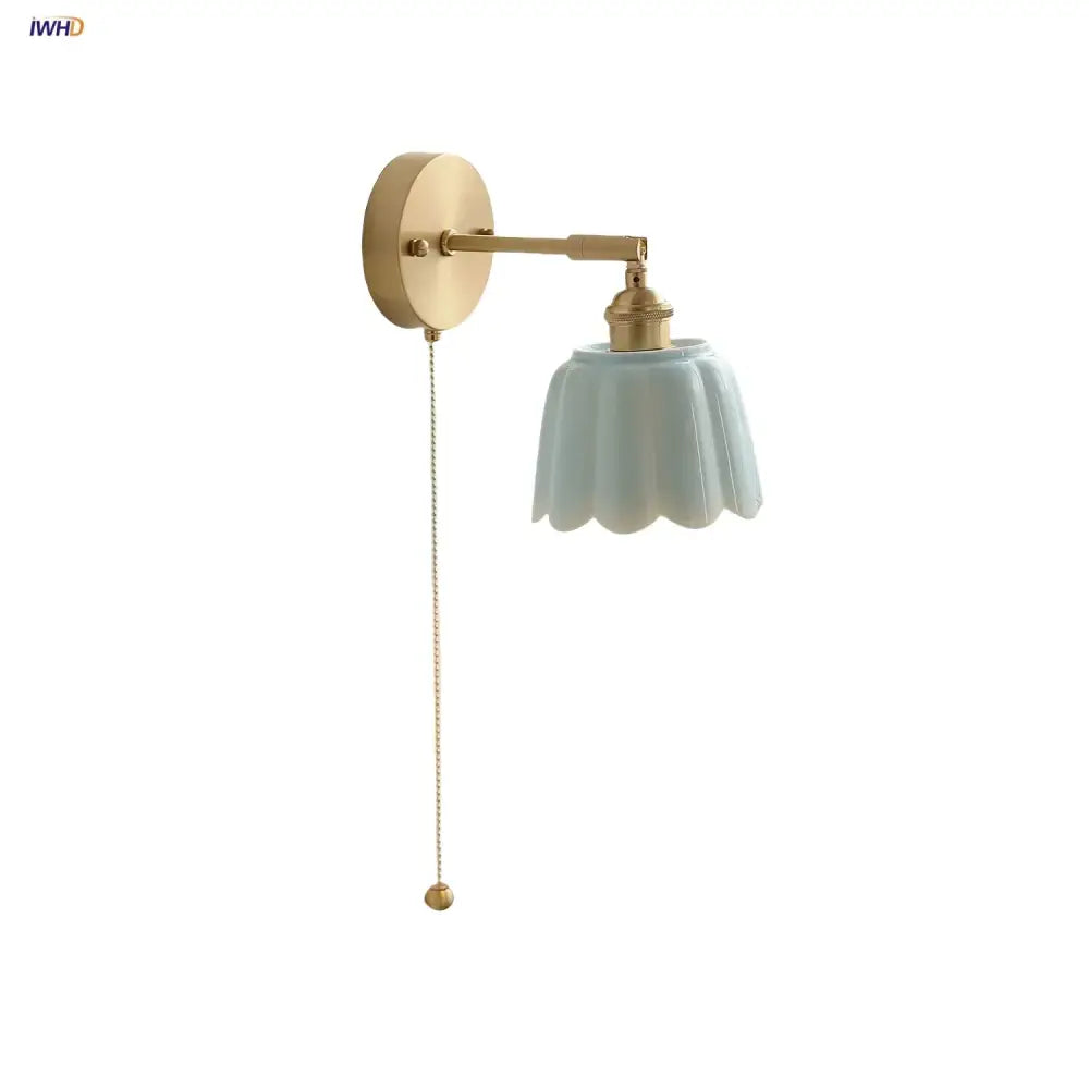 Floral light blue glass wall light fixture with gold-toned metal arm and pull chain for bedroom use