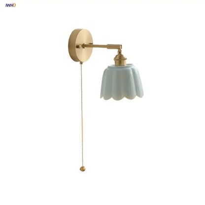 Floral light blue glass wall light fixture with gold-toned metal arm and pull chain for bedroom use