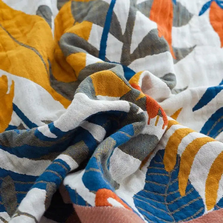 Floral mustard and white cotton throw blanket with vibrant tropical leaf pattern in yellow blue gray and orange hues decorbites cotton throw