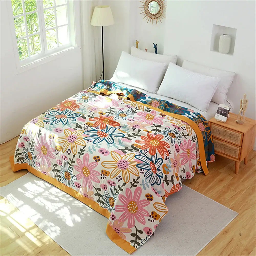 A floral pink and blue cotton gauze towel blanket with vibrant blossoms and a warm yellow border for cozy decorbites decor