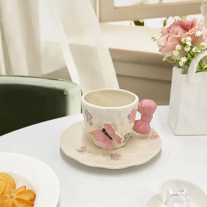 A delicate white ceramic cup and saucer set with pink butterfly and decorbites bowknot ceramic handle decor