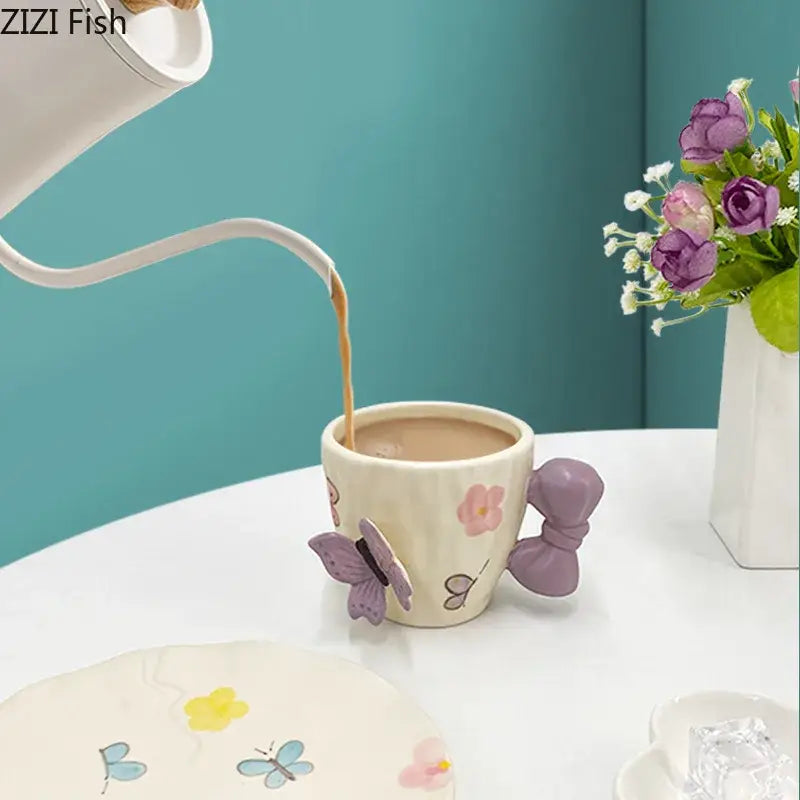 Cream-colored ceramic cup with pastel floral patterns and purple butterfly decorbites bowknot ceramic handle in saucer set