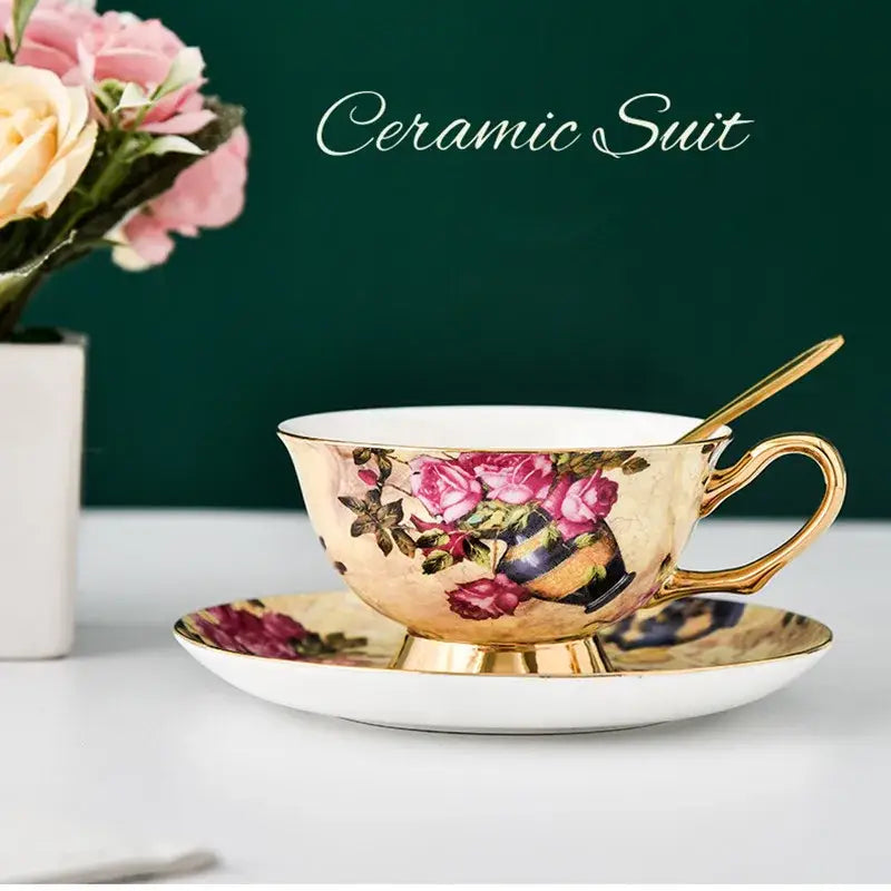 Elegant porcelain tea cup set with gold-trimmed edges and pink rose floral pattern on warm golden background