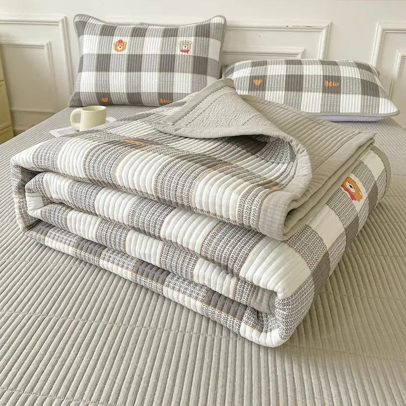 Gray and white checkered quilt with embroidered bear faces folded on bed sheets from decorbites cartoon small fresh collection