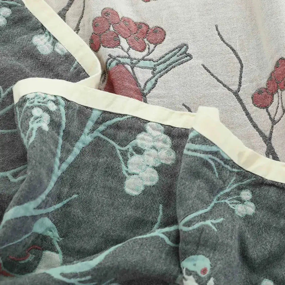 Gray cotton gauze summer blanket featuring a delicate red and white berry botanical print with cream stitched border