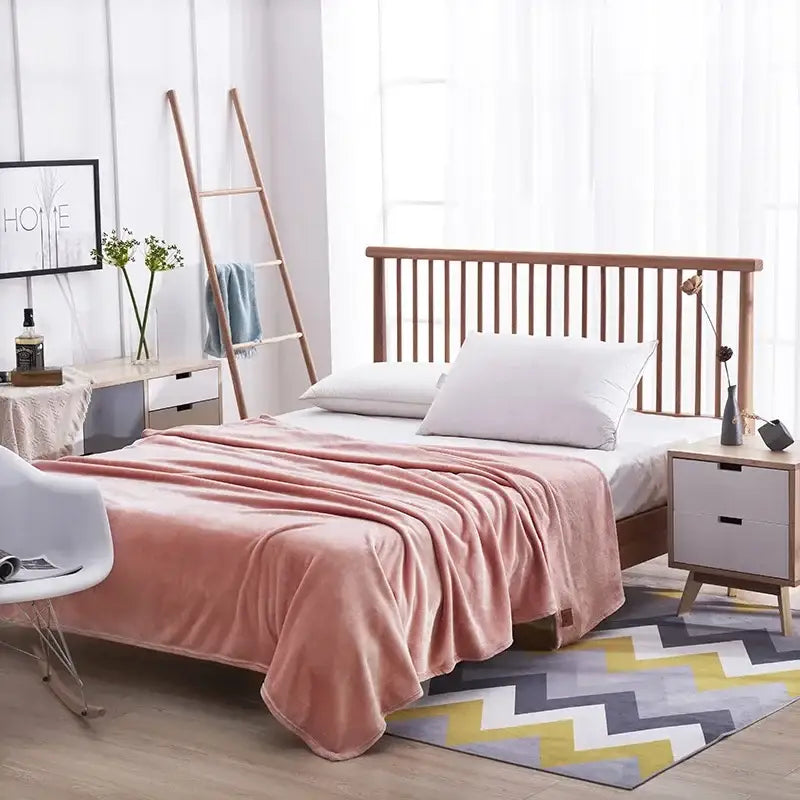 Soft pink plush blanket draped over wooden bed showcasing corerbites coral fleece flannel flower bedroom decor