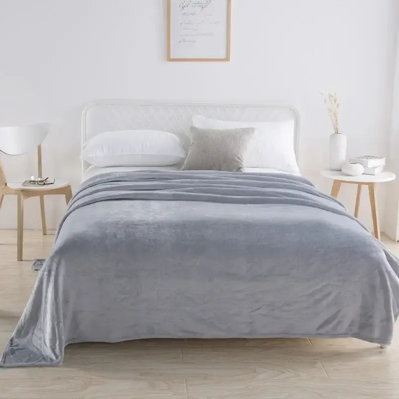 A soft plush gray throw blanket with velvety texture draped on bed in decorbites coral fleece flannel flower style