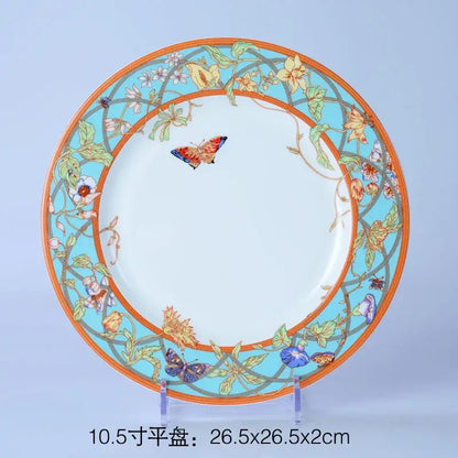 A decorative bone dinnerware set plate with a vibrant turquoise border floral and butterfly motifs and orange rim