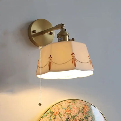 Vintage-style brass led wall light with cream ceramic shade featuring delicate brown floral and chain patterns for bedroom use