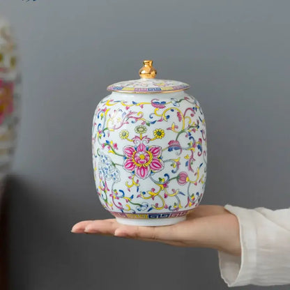 Floral white enamelled porcelain tea caddy ginger jar with gold lid knob and vibrant pink yellow blue floral patterns
