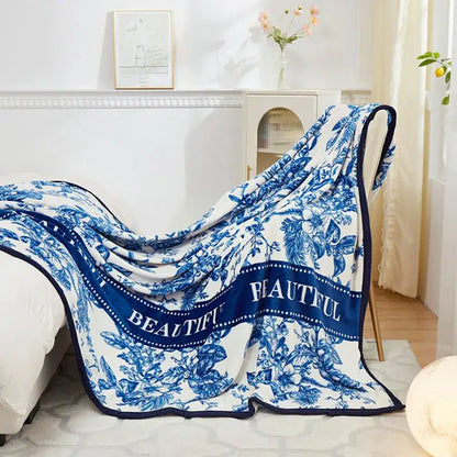 A soft white floral white and navy cozy flannel plush blanket with blue botanical patterns and beautiful script border