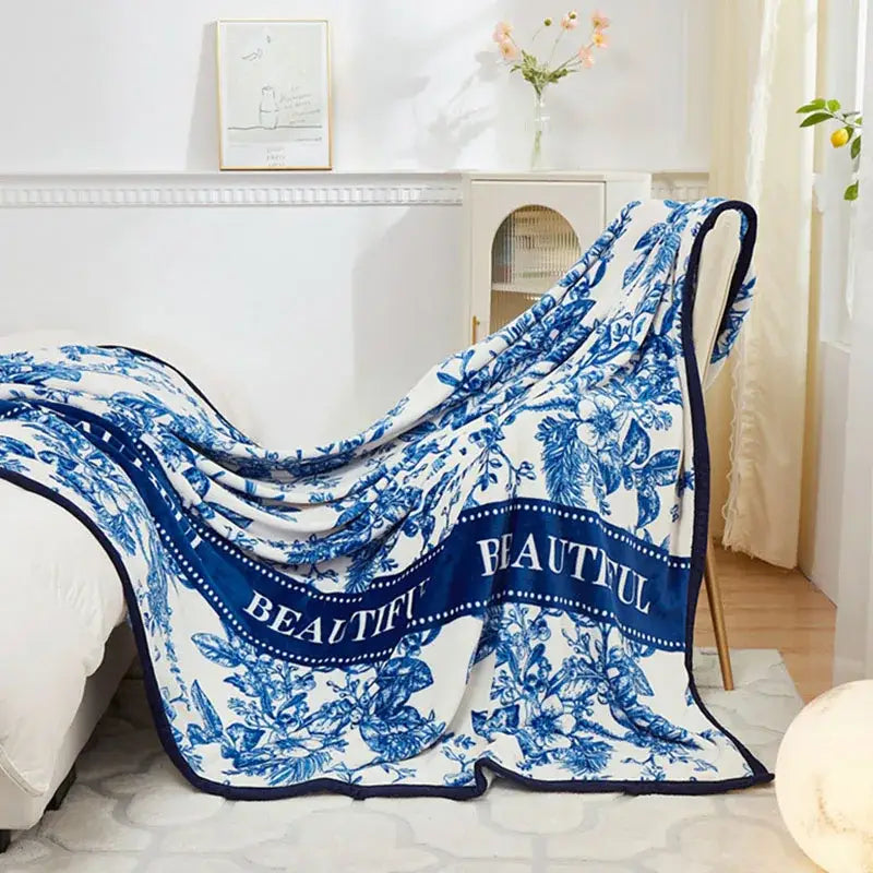 A soft white floral white and navy cozy flannel plush blanket with blue botanical patterns and beautiful script border