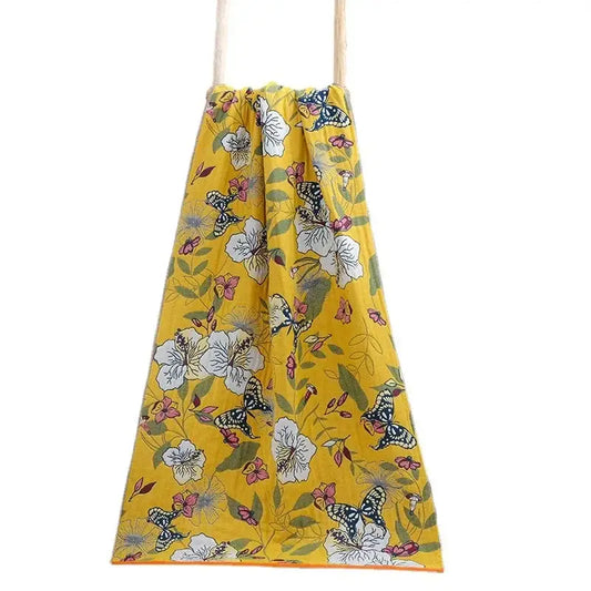 A vibrant yellow cotton gauze floral drawstring bag with white flowers, pink blossoms, and butterflies for decorbites bath towel wrap
