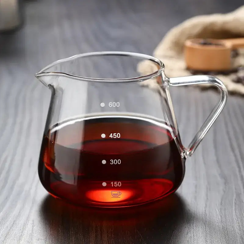 Fluted clear glass coffee pot with ribbed design and handle, filled with dark red liquid, glass coffee pot for kitchen use