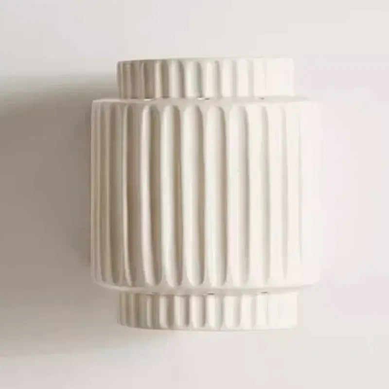 Off-white ceramic wall lamp with vertical ribbed texture and tiered cylindrical shape for decorbites cream white bedroom decor