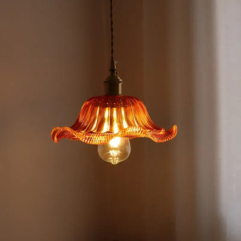 A warm amber pendant light with fluted petal design and brass hardware for decorbites green stripe glass decor