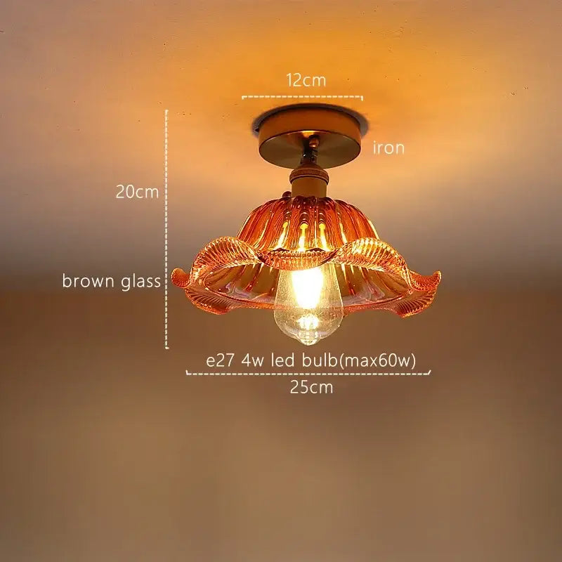 A warm-toned brown hand-blown glass pendant light with decorative petals and iron base for decorbites green stripe decor