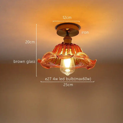 A warm-toned brown hand-blown glass pendant light with decorative petals and iron base for decorbites green stripe decor