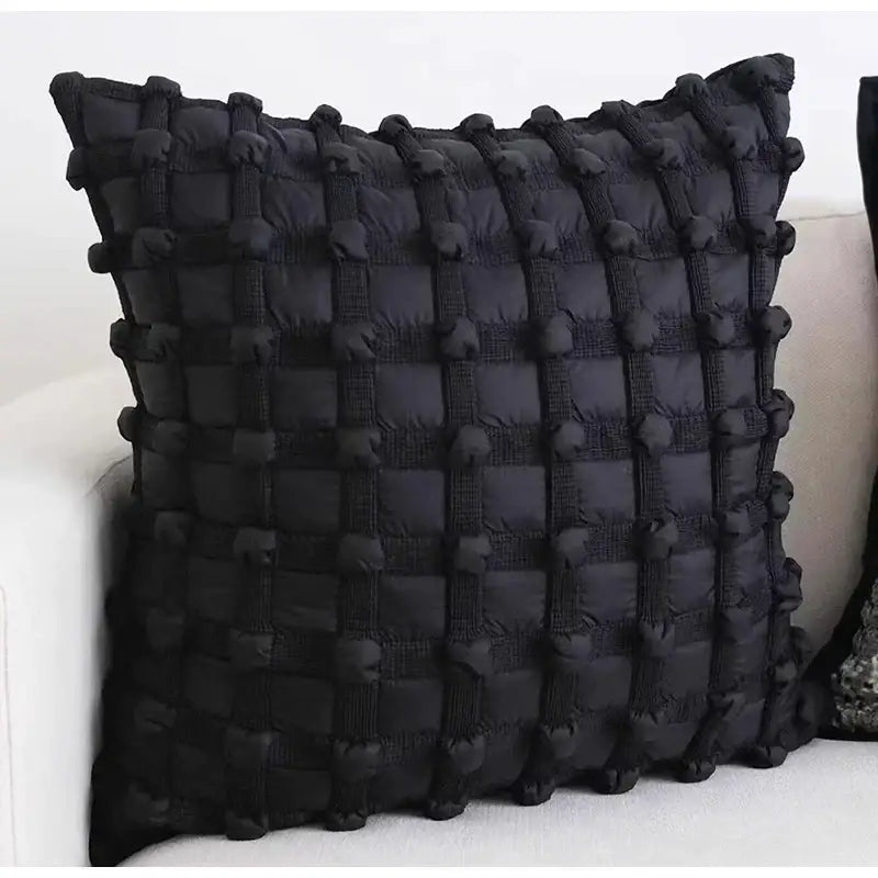 Black quilted cushion cover with textured grid pattern and pom-pom accents from decorbites french cream bubble collection