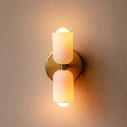 French cream double headed brass wall lamp with warm-toned frosted glass cylinders by decorbites french cream
