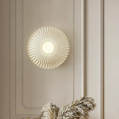 A cream-colored French cream wind sunburst wall lamp with frosted glass diffuser and metallic accents for bedroom decorbites