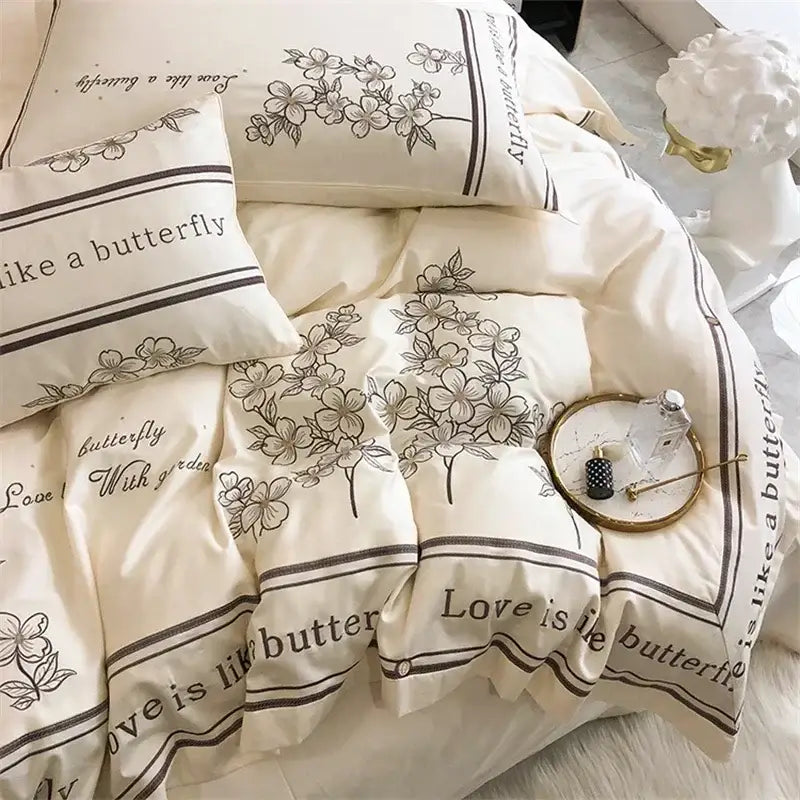 Cream-colored bedding set with black floral and love is like a butterfly text in decorbites french embroidered cotton design