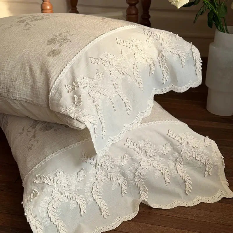 Cream-colored cotton pillowcases with delicate white floral embroidery and scalloped edges in french lace flowers bedding set