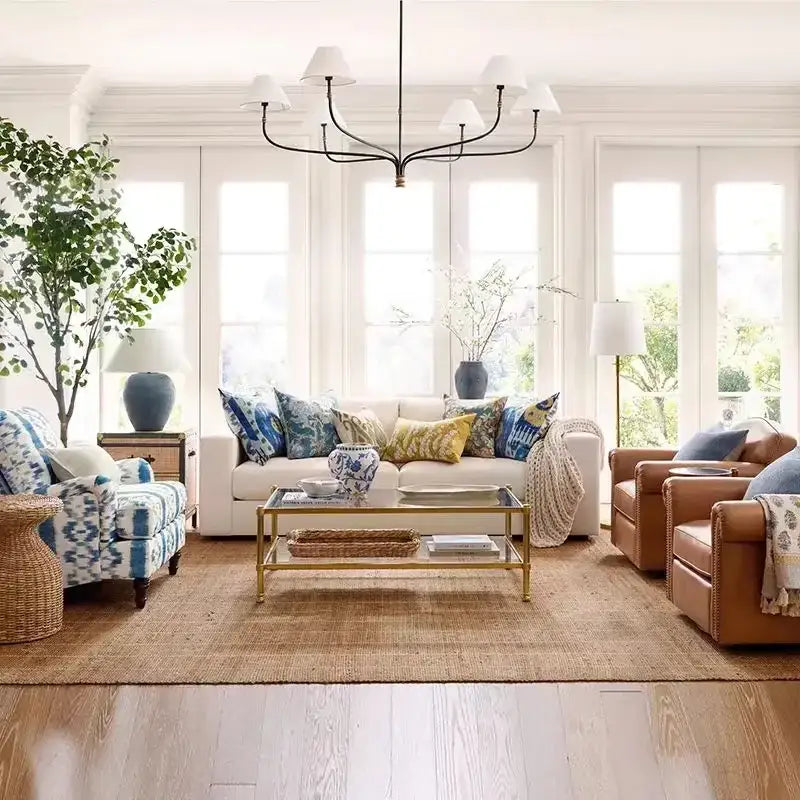 White sofa with blue and yellow pillows beneath a french minimalist black and brass cord pendant light with fabric shades