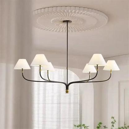 Black metal pendant light with six white fabric shades and gold accents for minimalist dining rooms