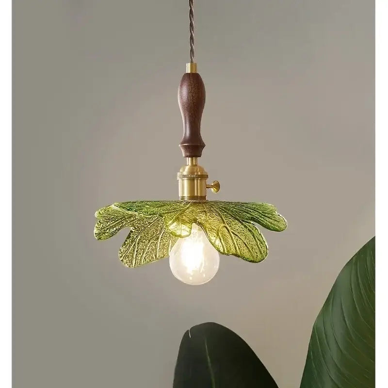 French minimalist green glass copper wood pendant lamp features a dark wood handle brass fittings and translucent leaves