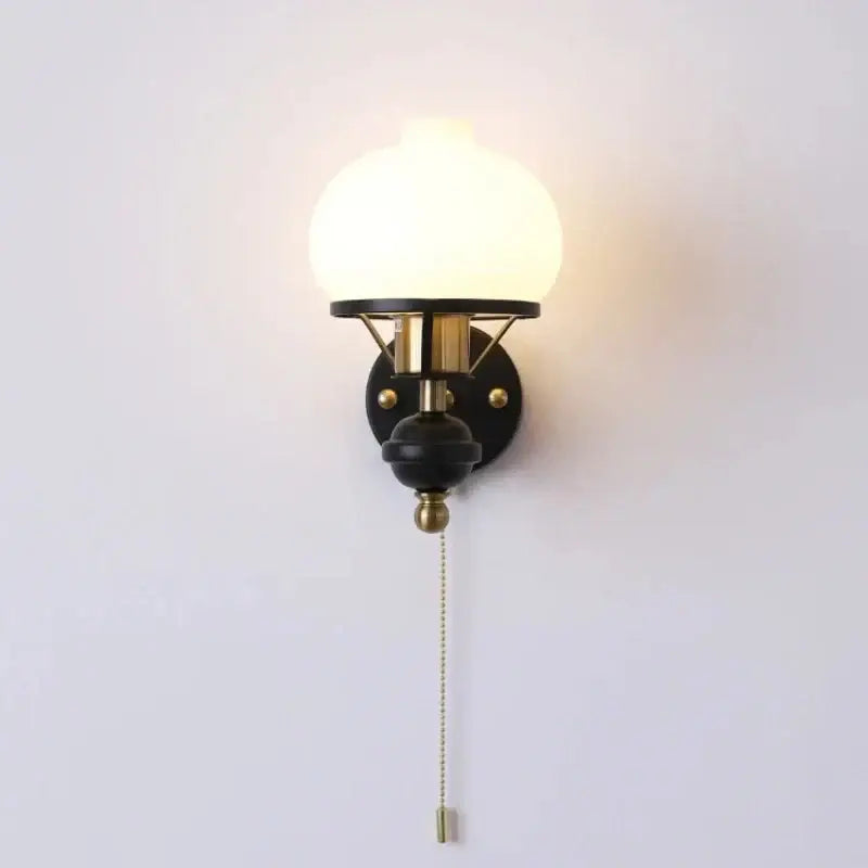French retro wall lamp with black and brass finish and frosted glass globe shade for living room use