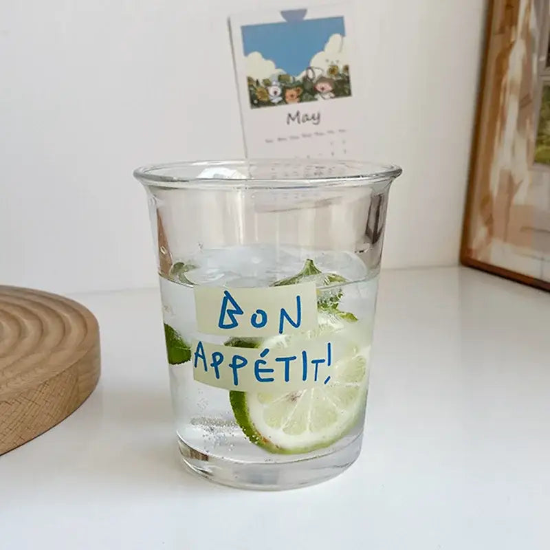 Clear glass tumbler cup with handwritten bon appétit label and lime slices for kitchen juice serving