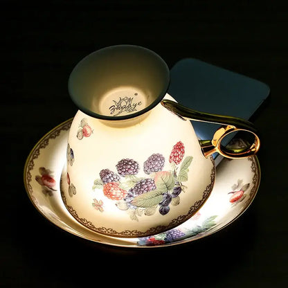 A cream-colored bone china tea cup with gold trim and hand-painted berry design from a French style teaware set