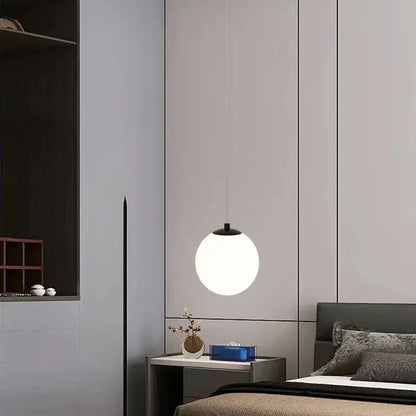 Minimalist frosted glass pendant light with a white spherical shade and black top for dining room lighting