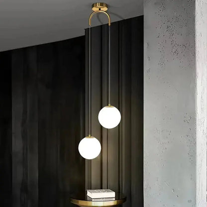 Modern brass pendant light with two frosted glass globes hanging from slender rods for dining room use