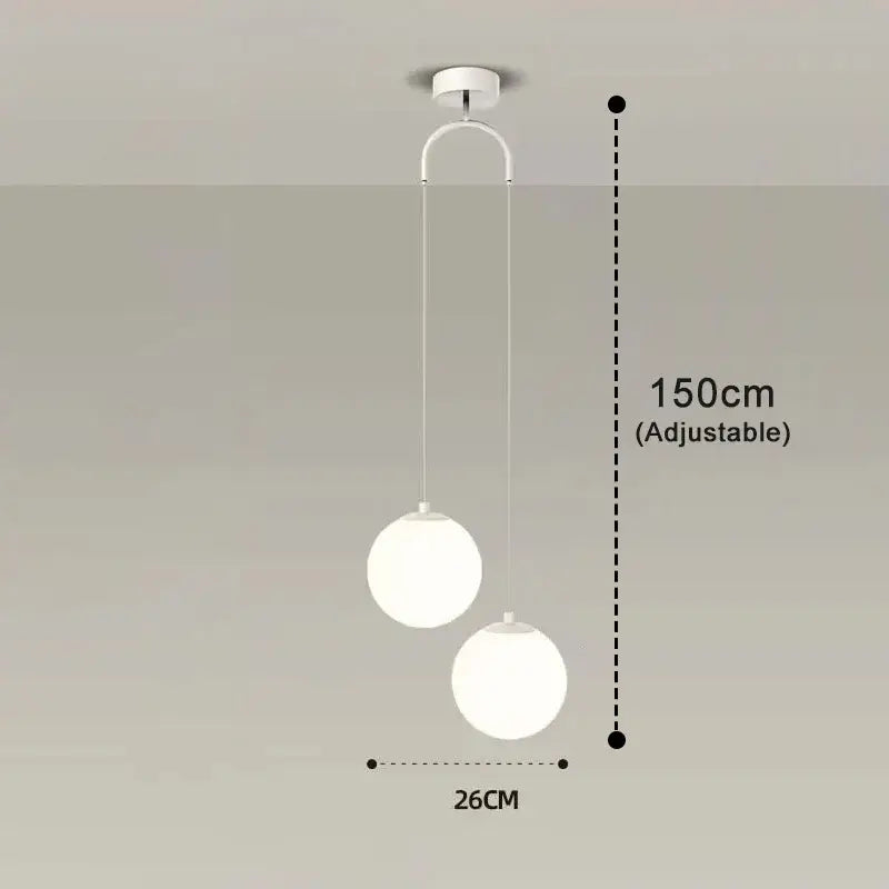 Frosted glass pendant light with white spherical shades and adjustable brass and black hanging length for dining room